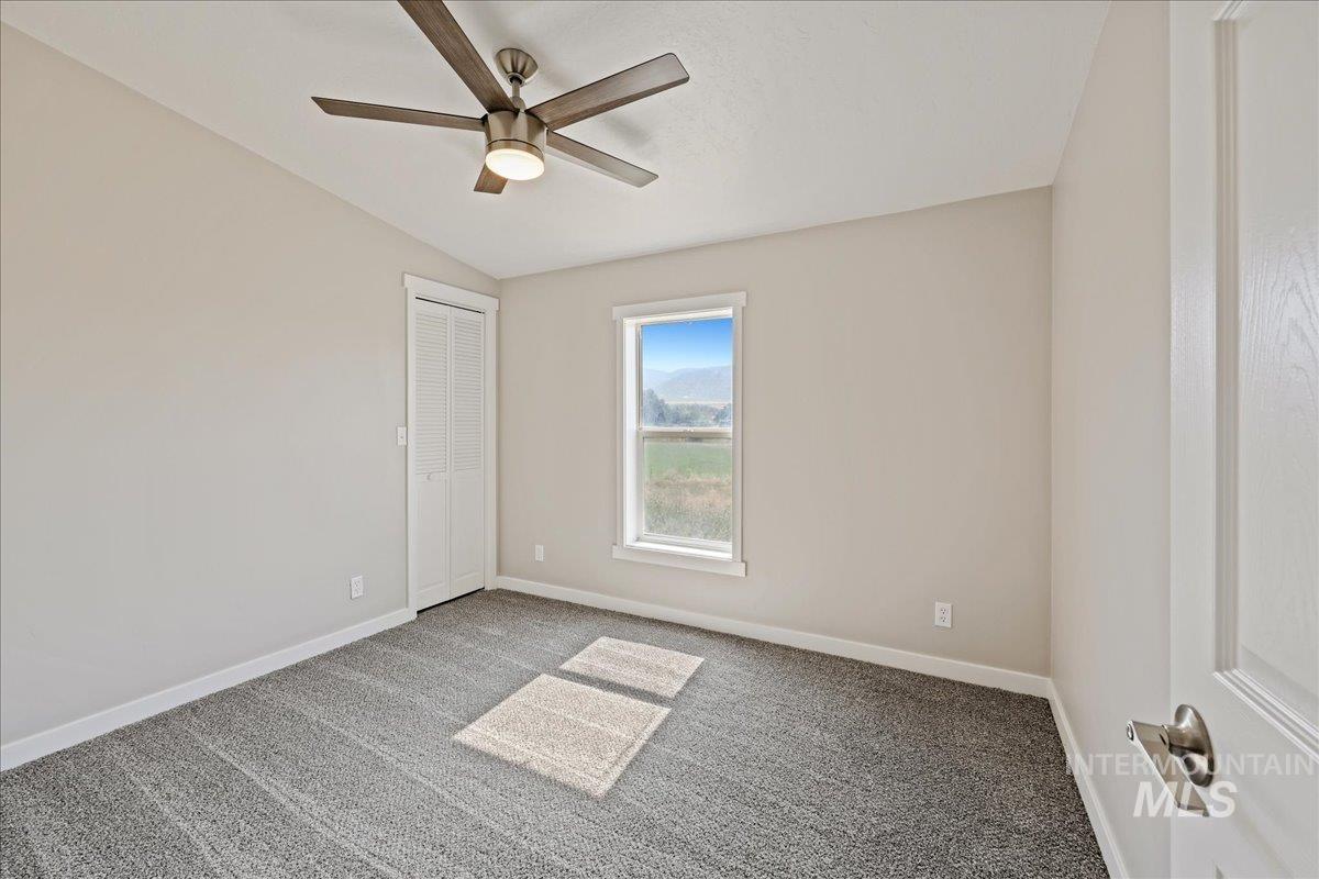 Carpeted empty room featuring lofted ceiling and ceiling fan