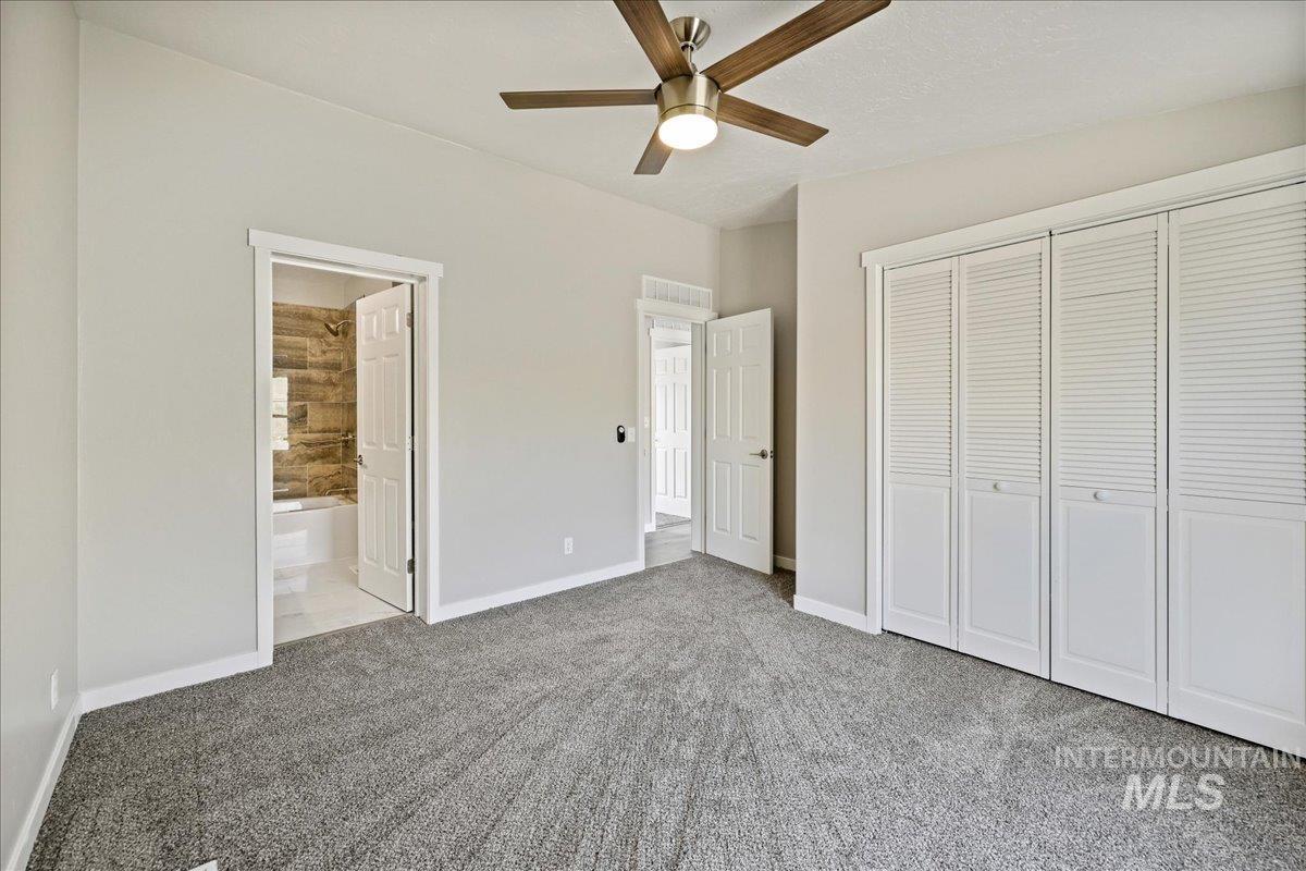 Unfurnished bedroom with a closet, carpet floors, ceiling fan, and ensuite bath