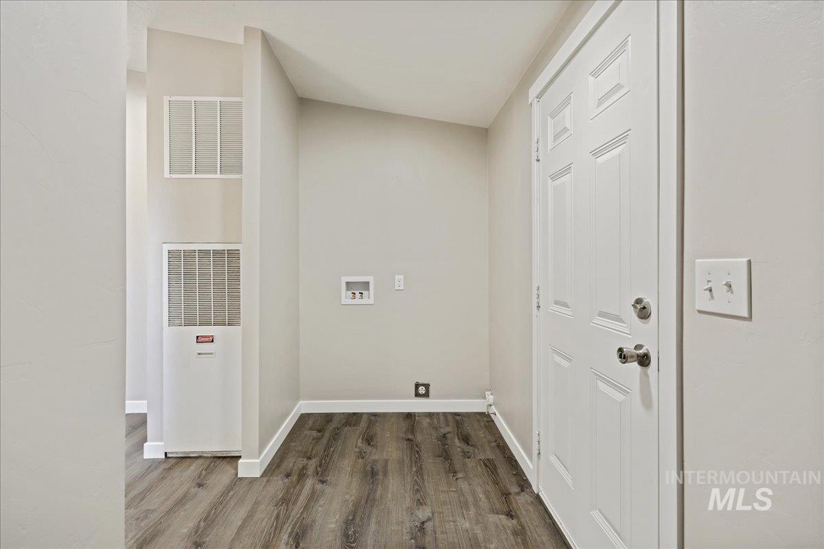 Laundry area with dark wood-style floors, a heating unit, and hookup for a washing machine