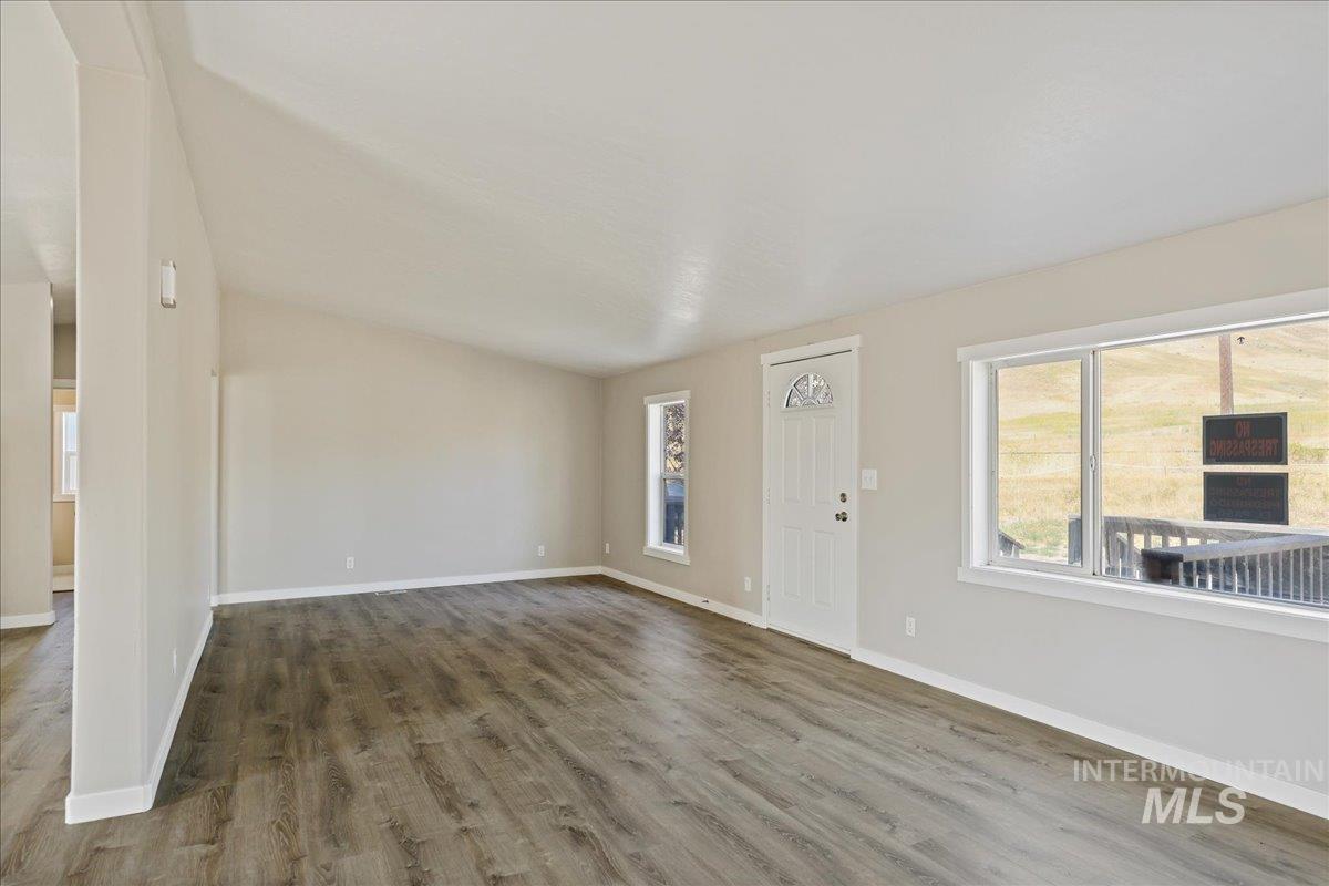 Unfurnished living room with wood finished floors and baseboards