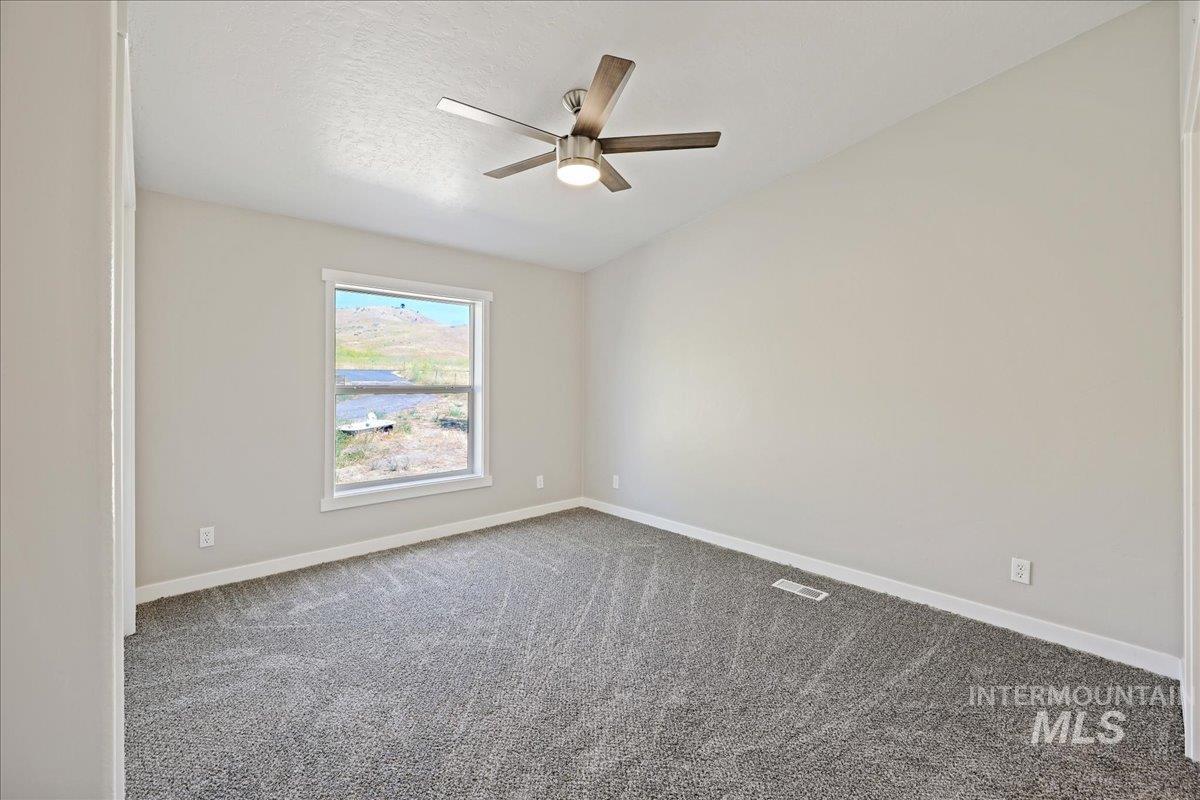 Carpeted empty room featuring a textured ceiling and a ceiling fan