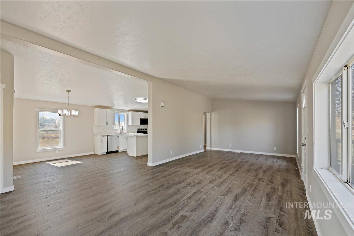 Unfurnished living room with dark wood finished floors, a chandelier, and a textured ceiling