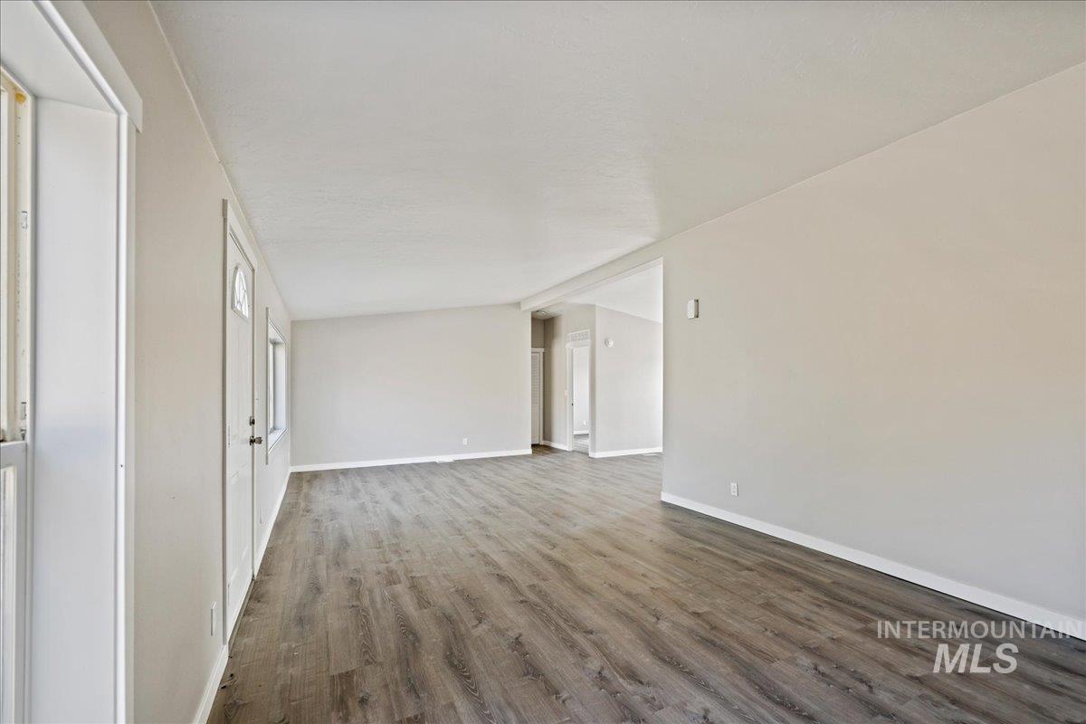 Unfurnished living room featuring wood finished floors and baseboards