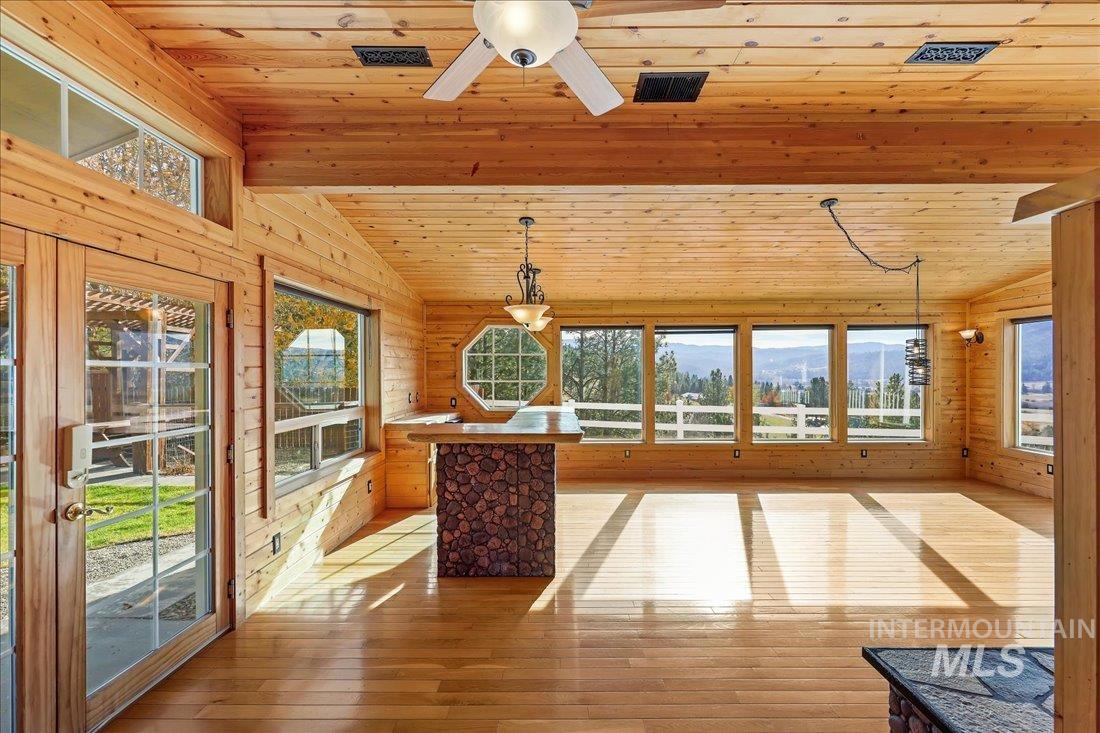 Unfurnished sunroom featuring plenty of natural light and vaulted ceiling