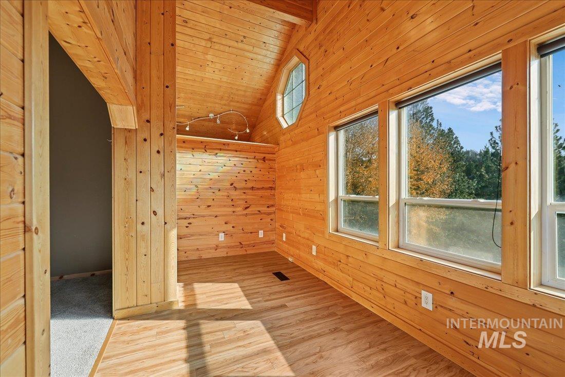 Additional living space featuring wood walls, wood finished floors, plenty of natural light, and wood ceiling