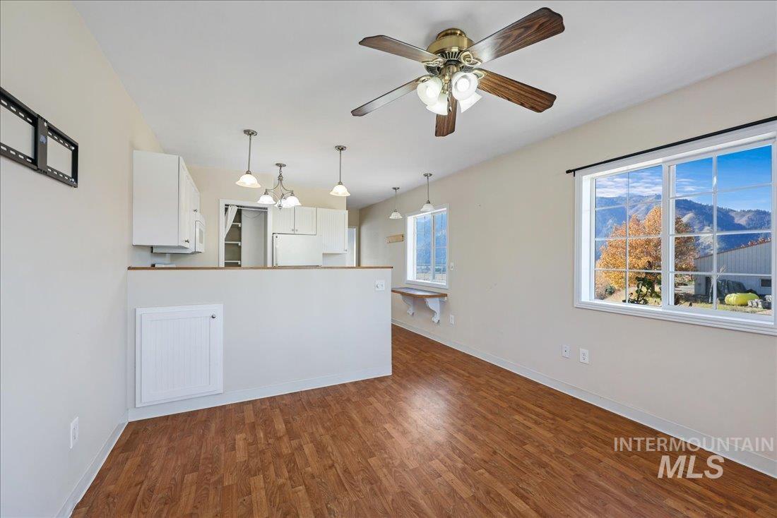 Kitchen with white cabinets, dark wood-type flooring, a peninsula, pendant lighting, and a ceiling fan