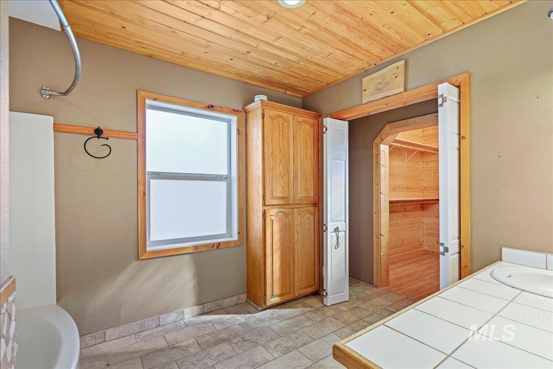 Bathroom featuring wooden ceiling, vanity, a shower, and a textured wall