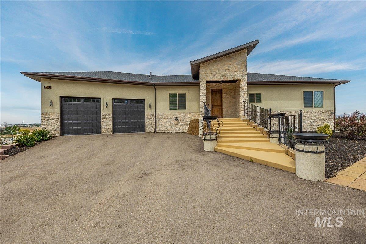 Stucco and stone exterior featuring a prominent entryway with a dark wood door, wrought iron railings, and a multi-level staircase
