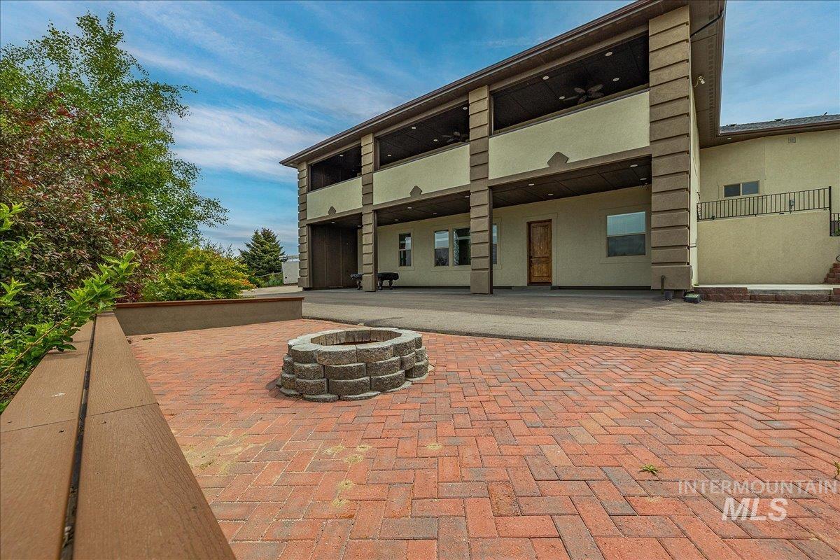 Brick paver patio featuring a stone fire pit, bordered by a built-in planter and a composite wood bench
