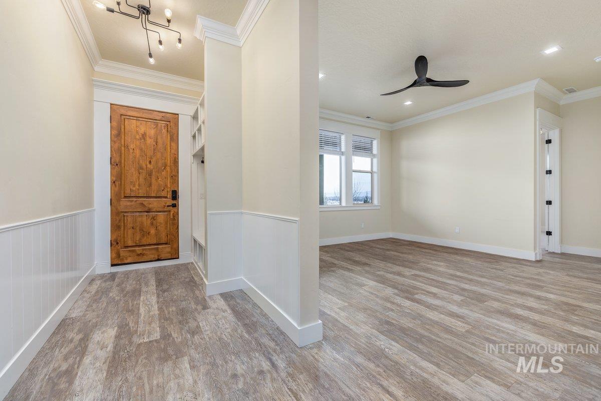 Entryway featuring light wood-type flooring, a ceiling fan, and ornamental molding