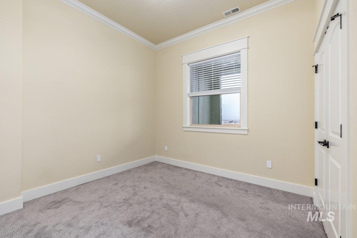 Unfurnished bedroom with carpet flooring, ornamental molding, a barn door, and a textured ceiling