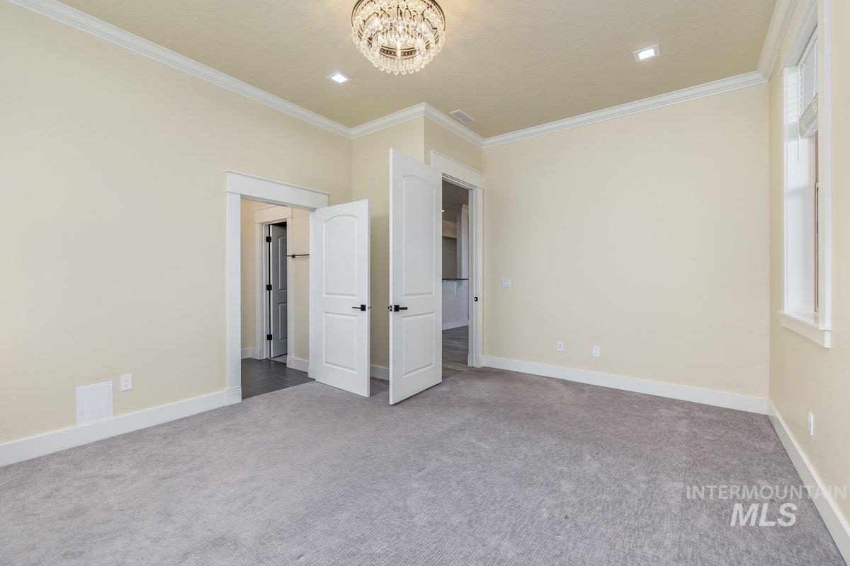 Unfurnished bedroom featuring ornamental molding, carpet flooring, and a chandelier