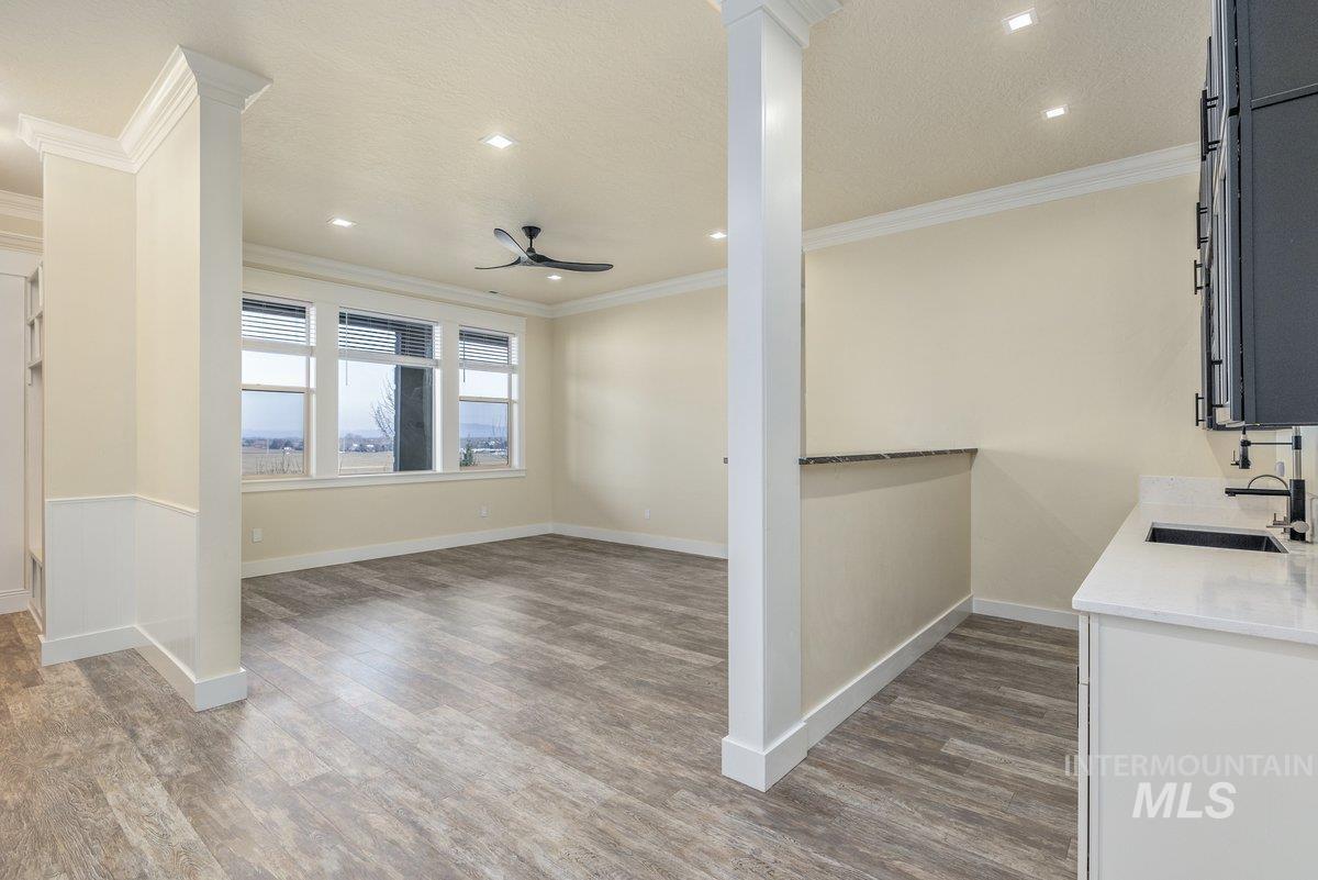 Kitchen with light stone counters, dark wood-style flooring, ceiling fan, ornamental molding, and recessed lighting