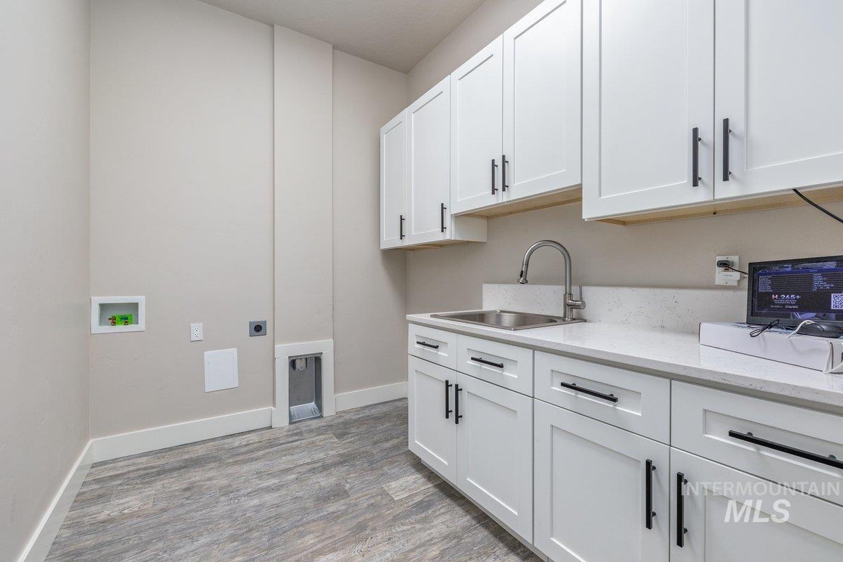 Laundry area with electric dryer hookup, light wood-style floors, hookup for a washing machine, and cabinet space