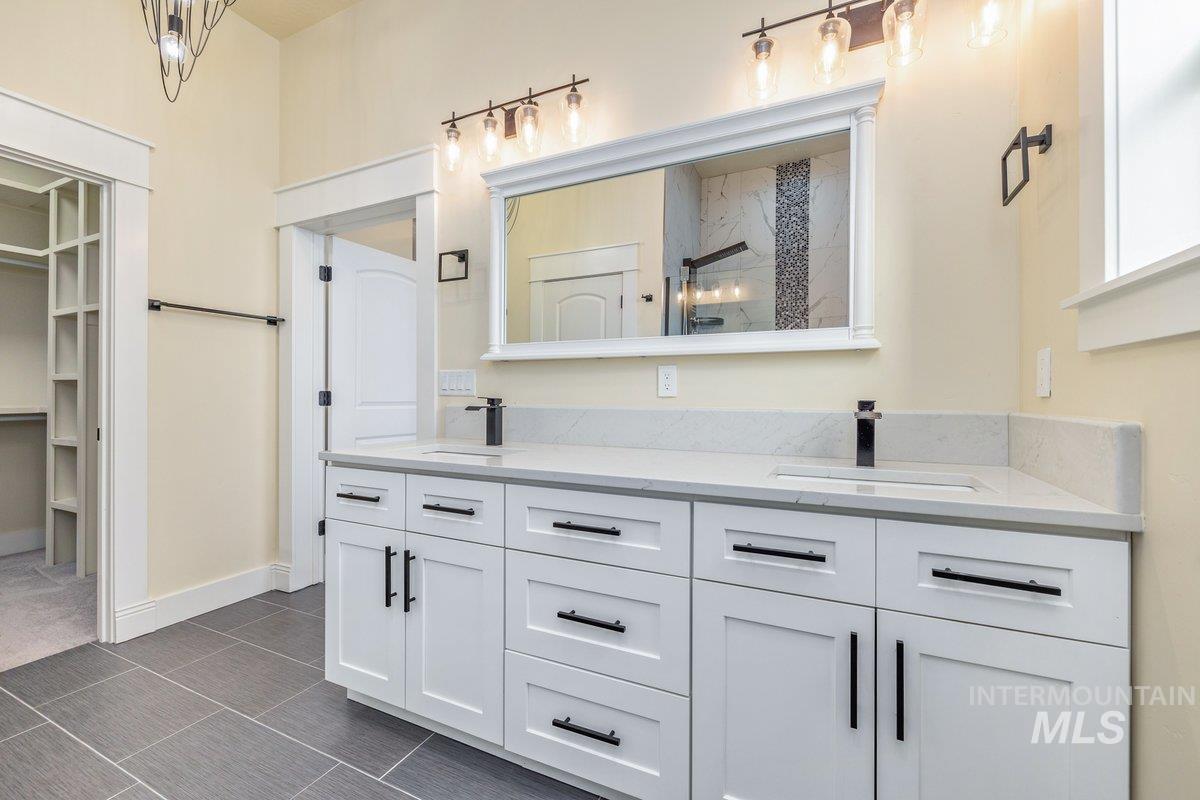 Bathroom with double vanity, a shower, and a walk in closet