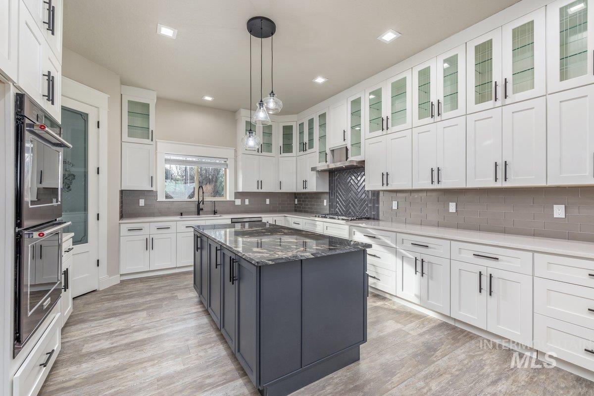 Kitchen with dark stone countertops, pendant lighting, white cabinetry, appliances with stainless steel finishes, and a center island