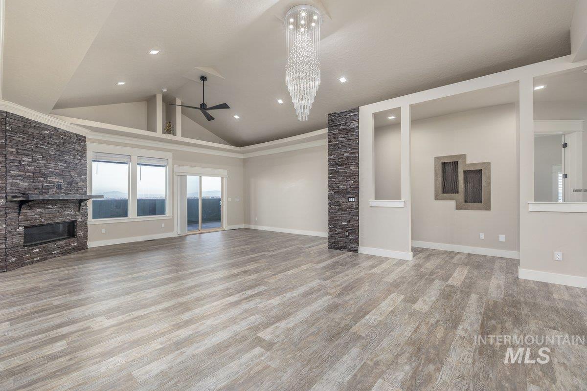 Unfurnished living room featuring a fireplace, ceiling fan, light wood-style flooring, and high vaulted ceiling