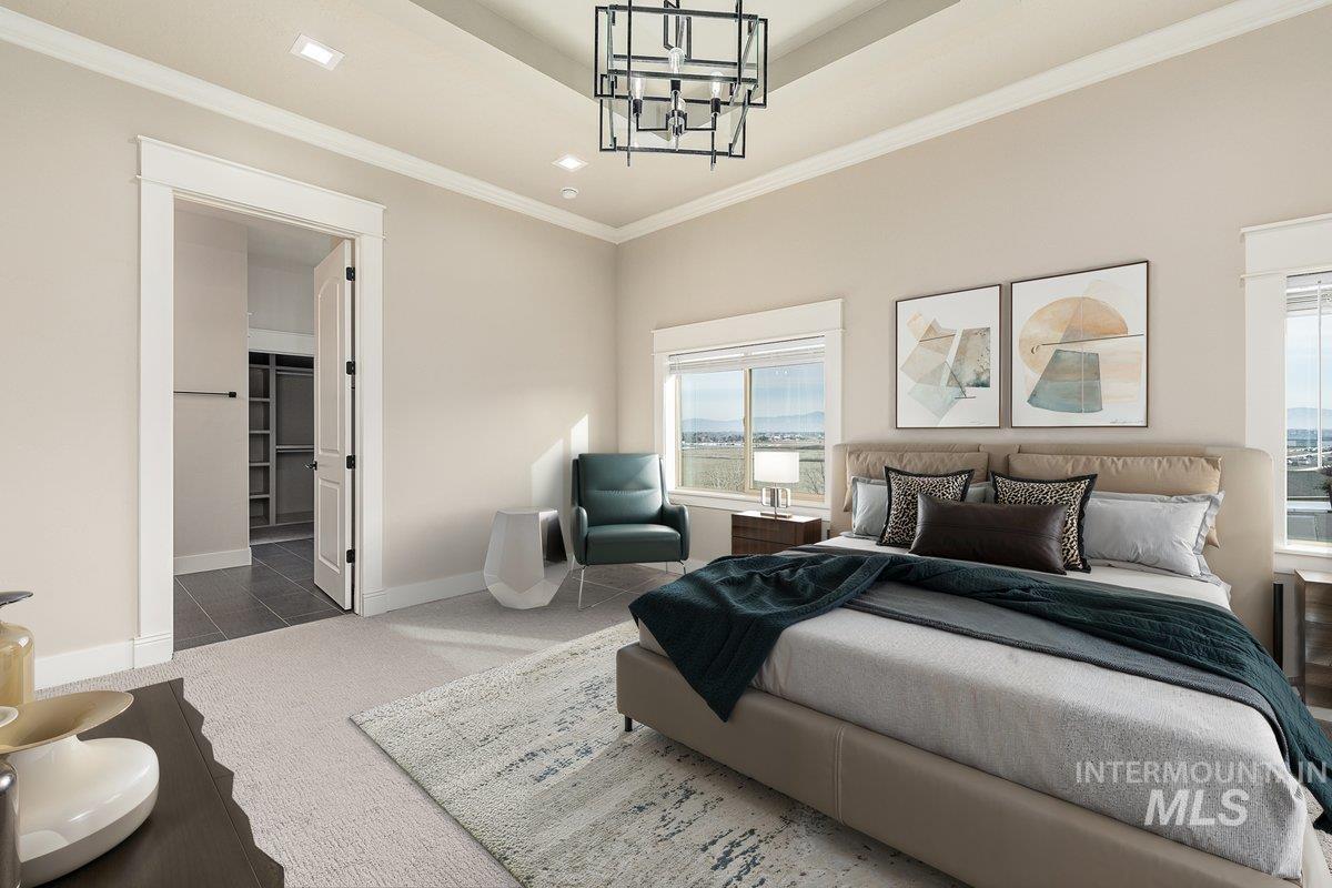 Bedroom with carpet, crown molding, a chandelier, ensuite bathroom, and a raised ceiling
