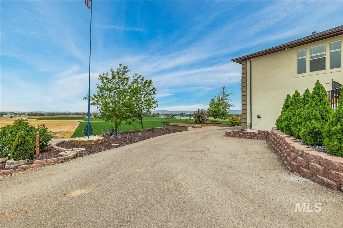 Paved driveway with a retaining wall, stucco exterior, multiple windows, and a flagpole