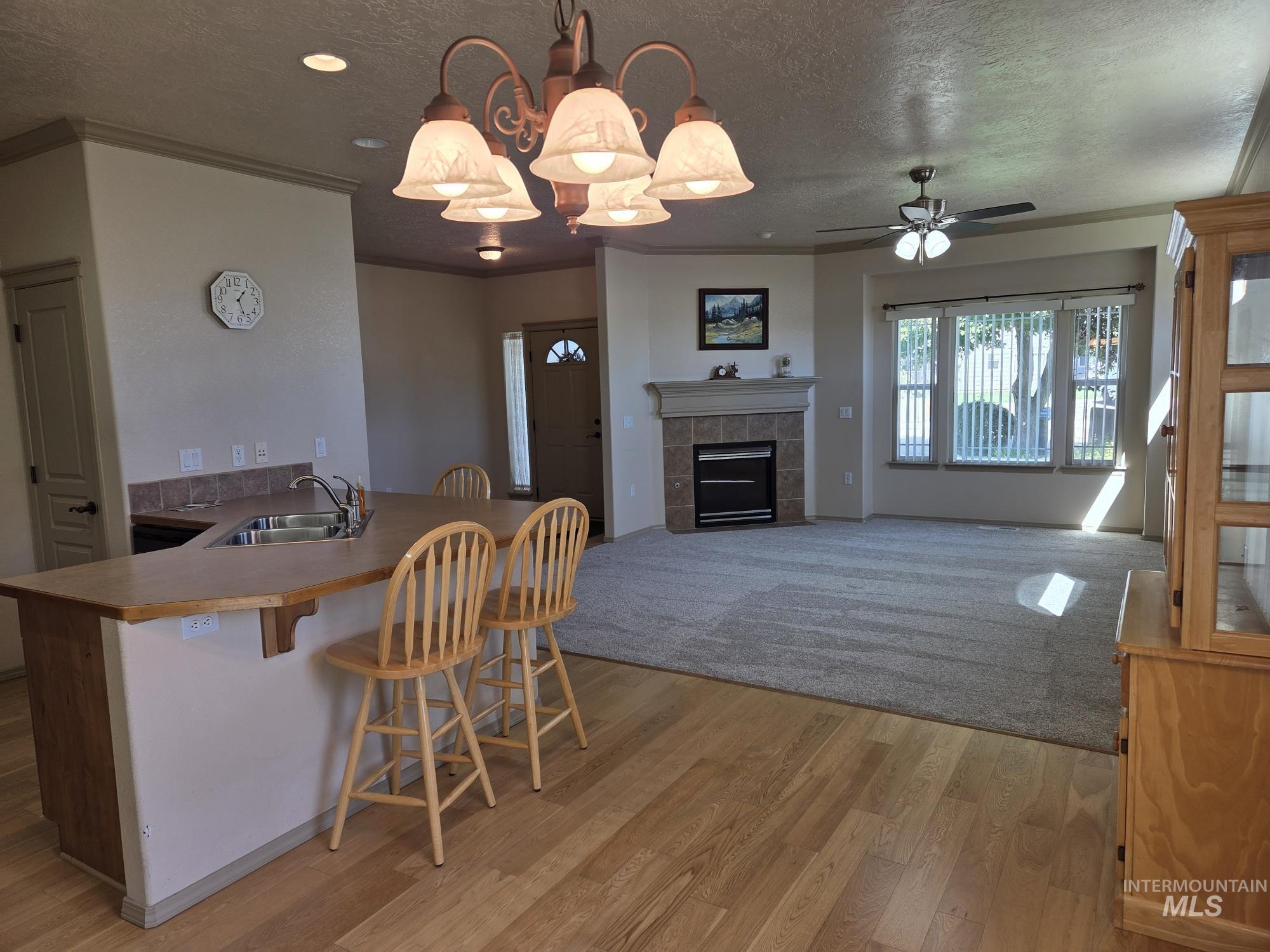 Kitchen with decorative light fixtures, ornamental molding, a kitchen breakfast bar, a peninsula, and a textured ceiling