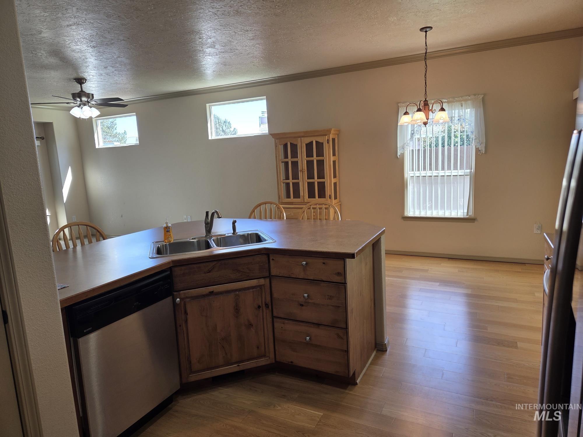 Kitchen with stainless steel appliances, a textured ceiling, ornamental molding, a ceiling fan, and dark wood-style floors