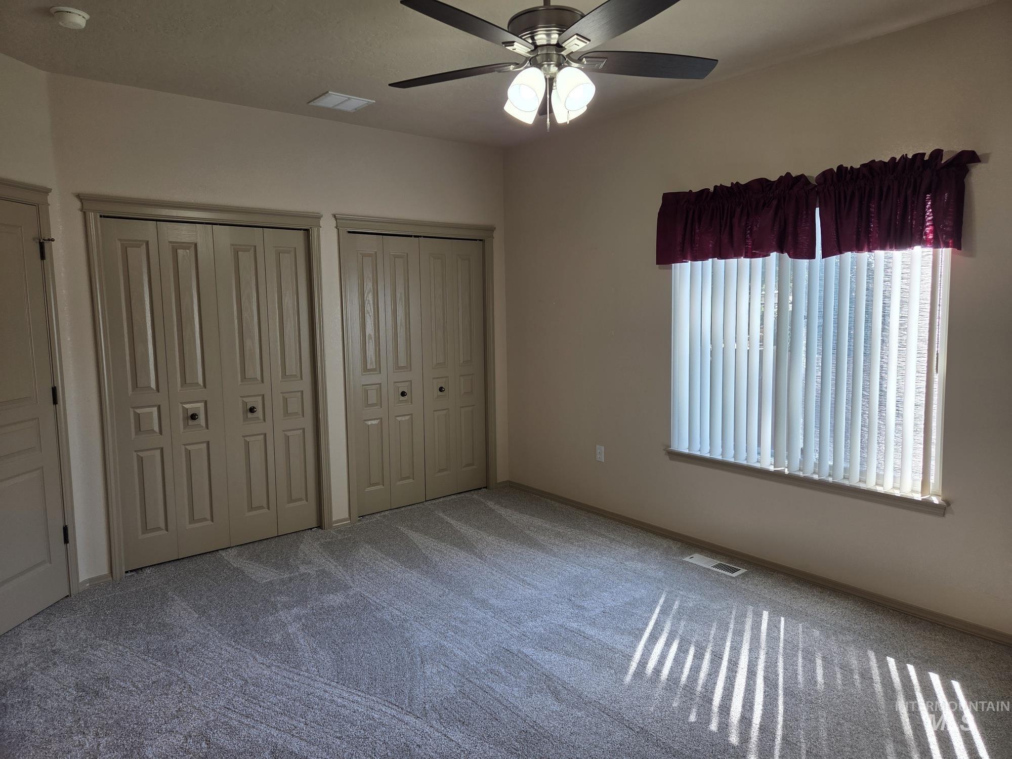 Unfurnished bedroom featuring multiple closets, carpet flooring, and a ceiling fan