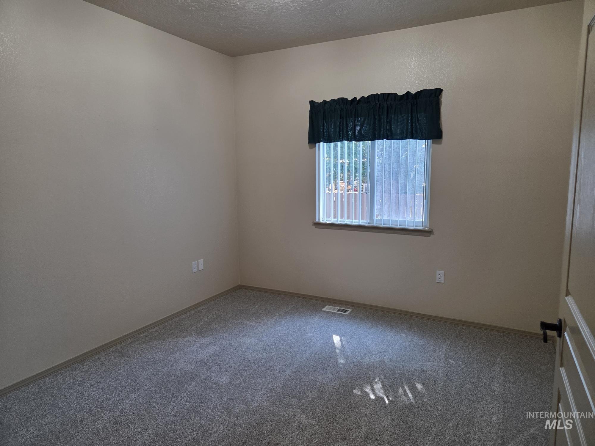 Empty room featuring carpet floors and a textured ceiling