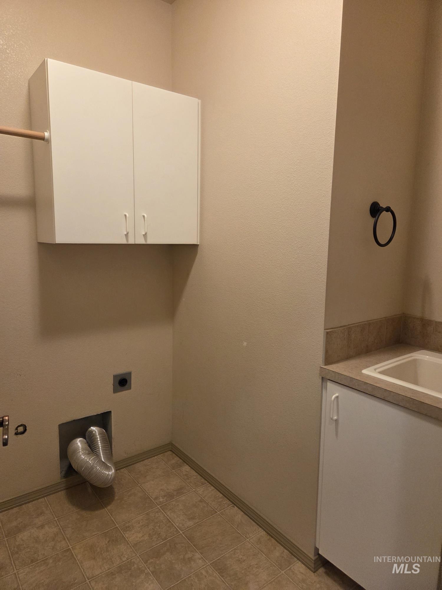 Laundry room with cabinet space, electric dryer hookup, and light tile patterned floors