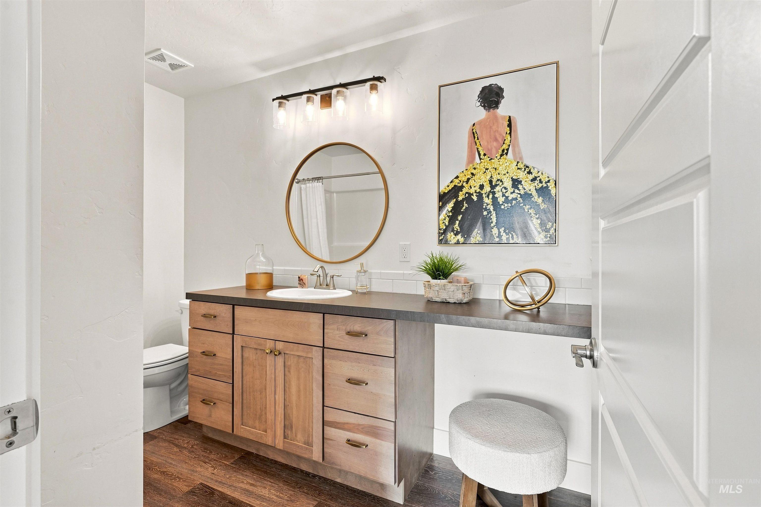 Bathroom featuring a wood-finish vanity with an integrated sink and dark countertop