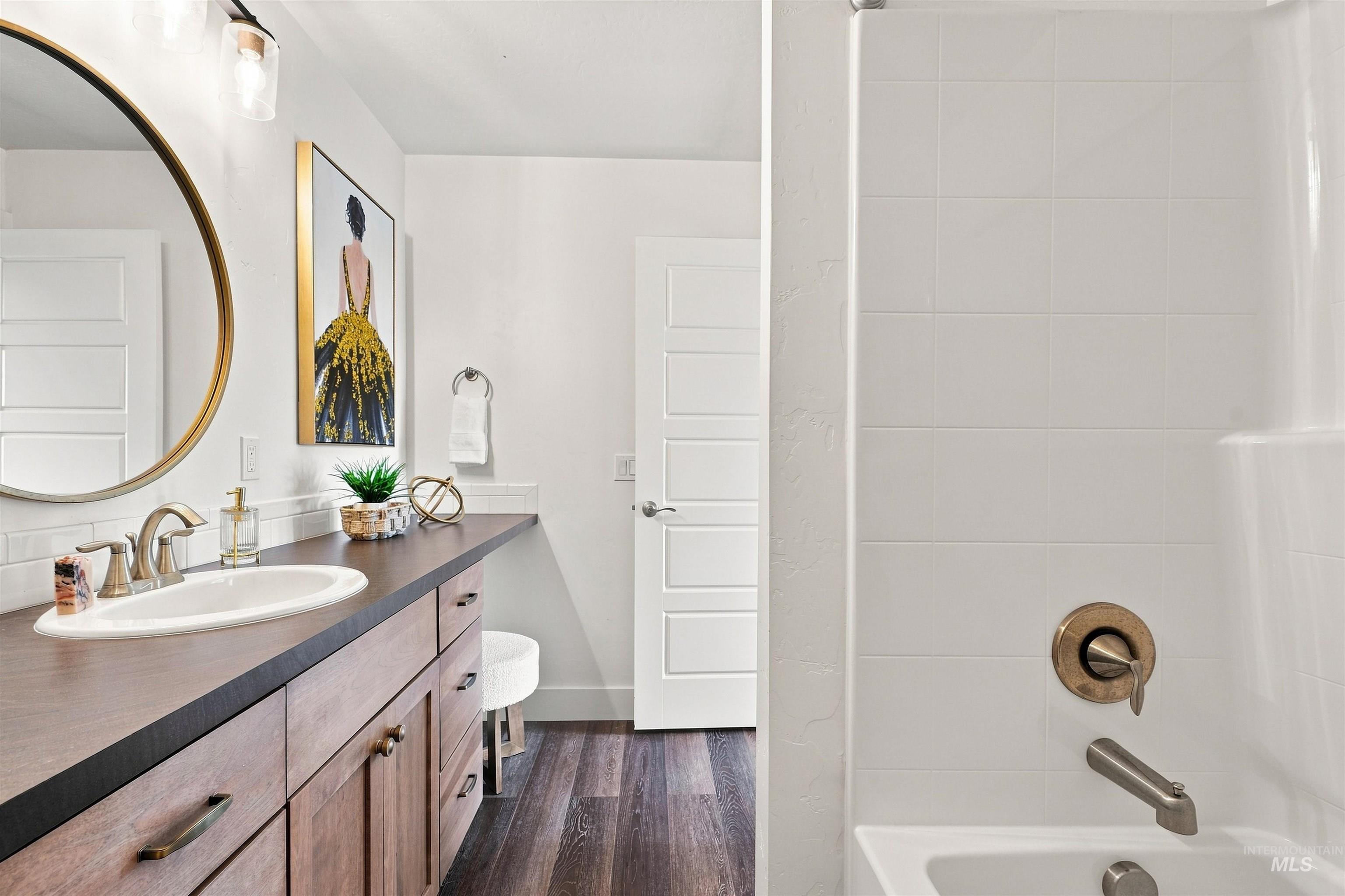 Bathroom featuring a single-sink vanity with wood-finish cabinetry, a dark countertop, and a circular mirror