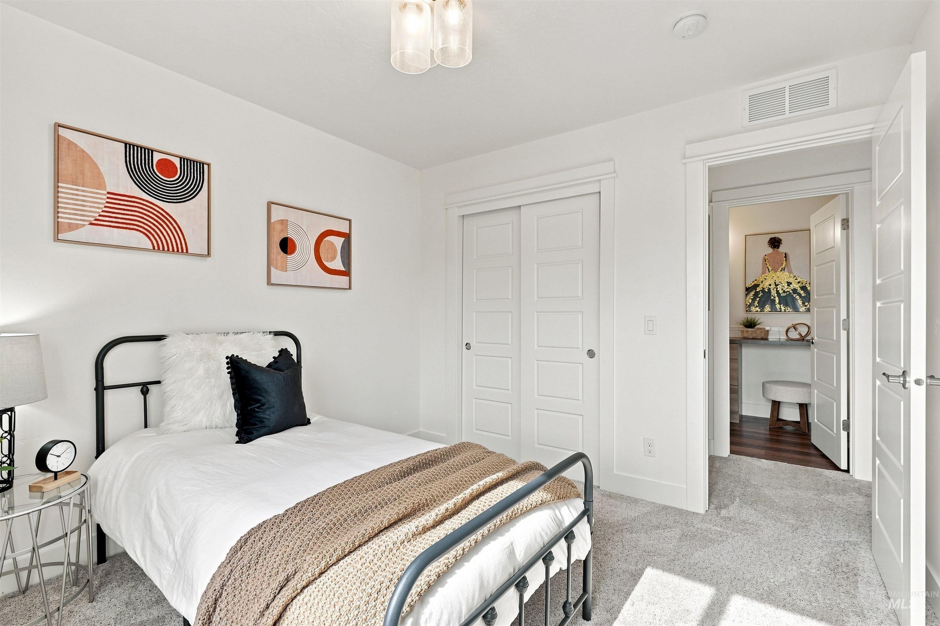 Carpeted room featuring a ceiling light fixture, white walls, and a closet with sliding panel doors