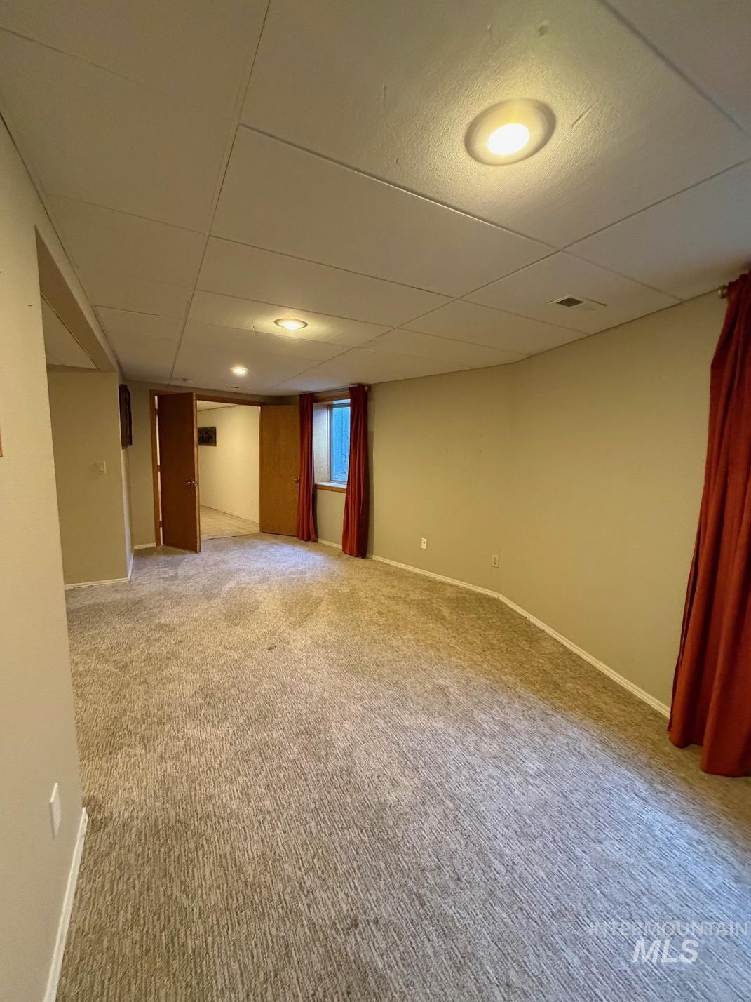Spare room with a drop ceiling and light carpet