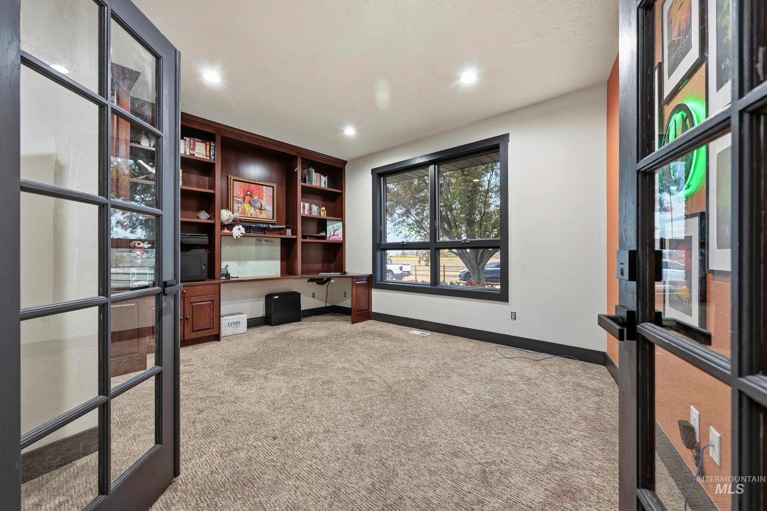 Unfurnished office with built in study area, light carpet, french doors, and recessed lighting