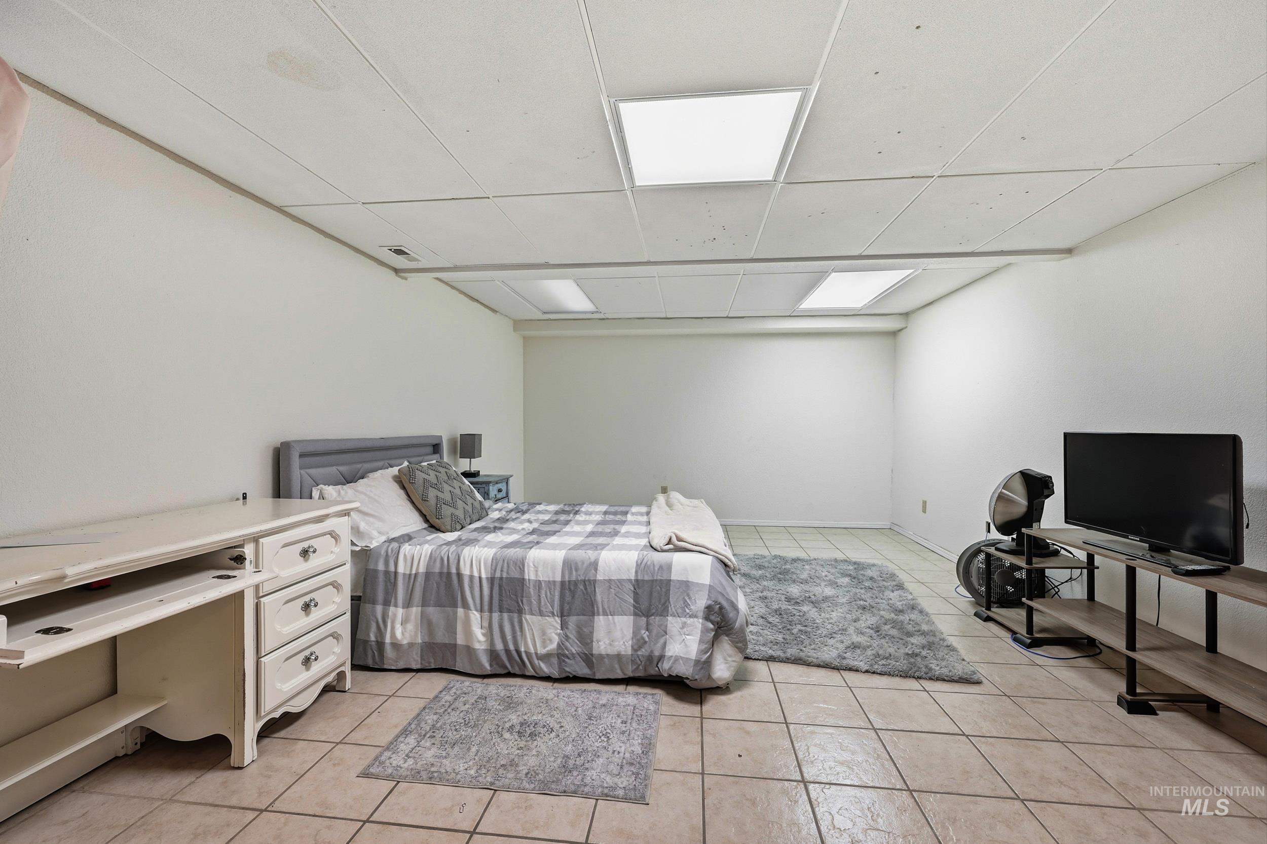 Bedroom featuring light tile patterned flooring and a drop ceiling