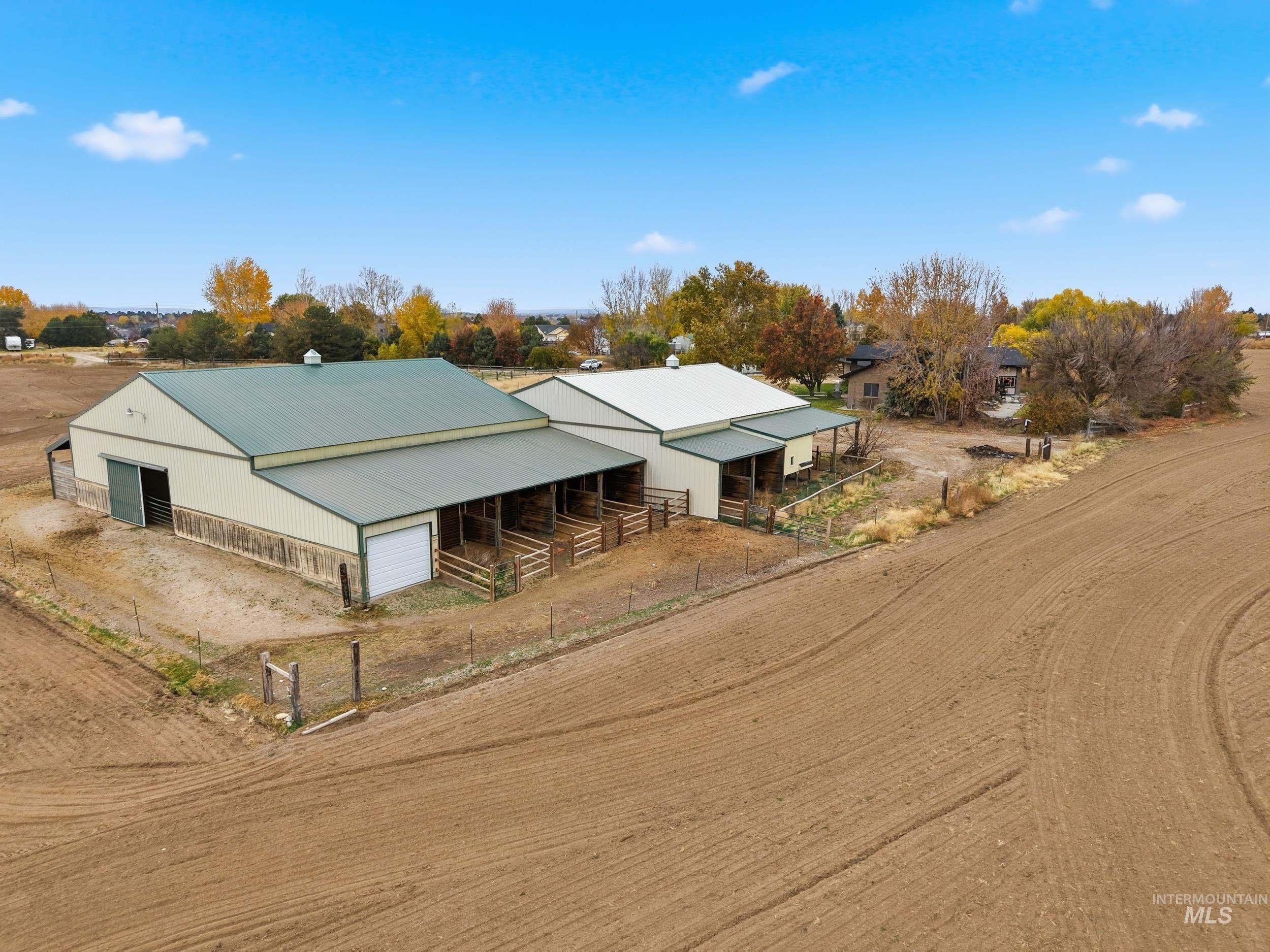 View of front of property featuring an exterior structure, an outdoor structure, a garage, driveway, and a metal roof