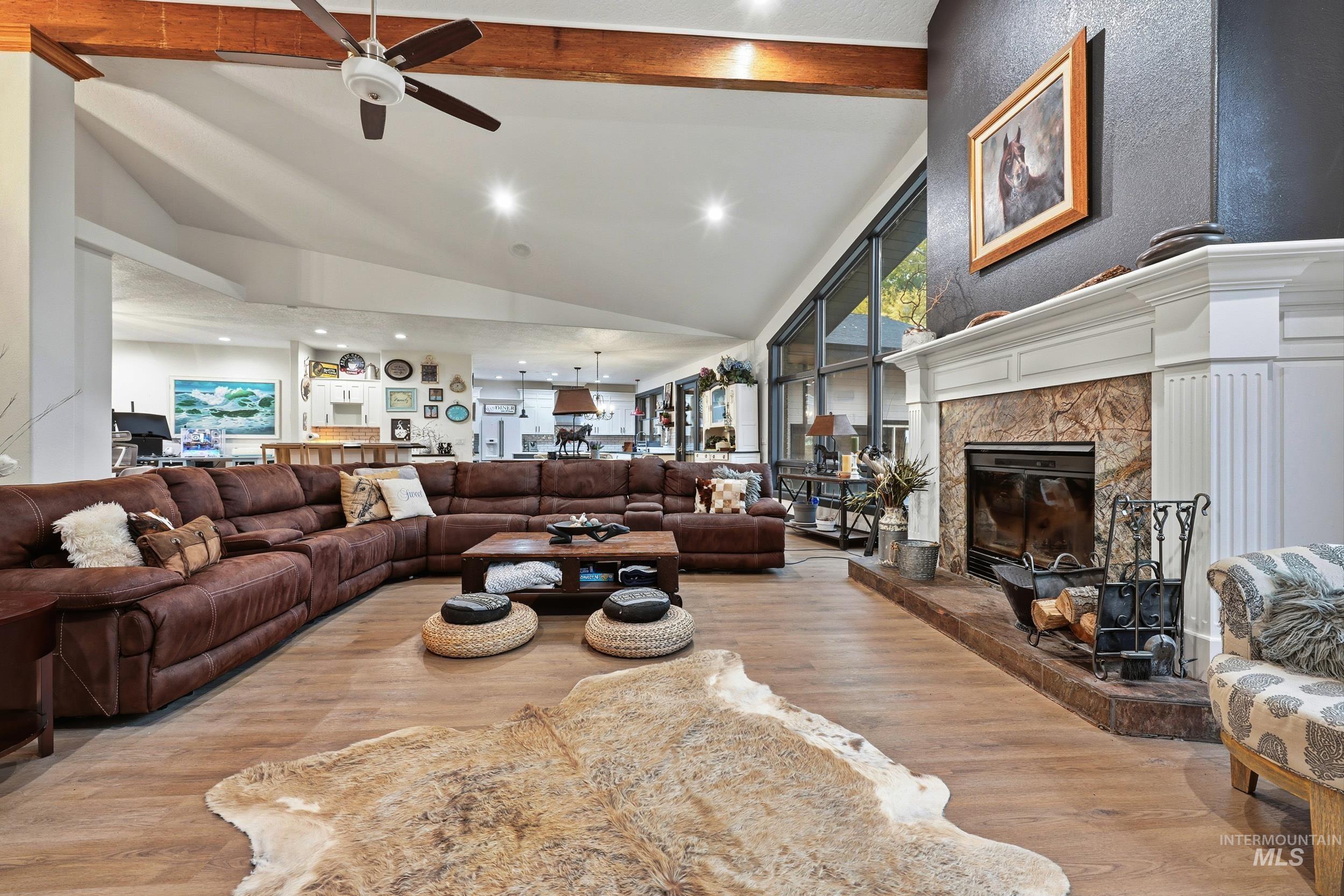 Living room featuring lofted ceiling, light wood-style floors, a fireplace, ceiling fan, and recessed lighting