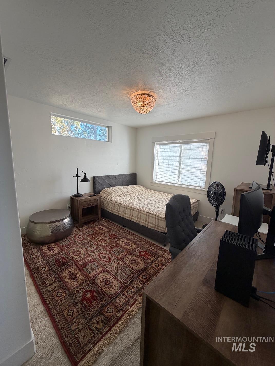 Bedroom featuring multiple windows, a textured ceiling, carpet floors, and a desk