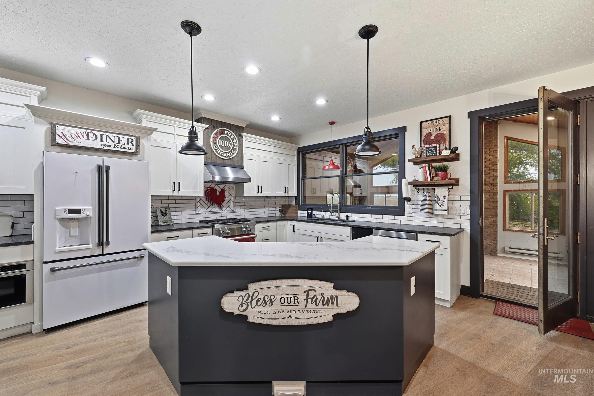 Kitchen featuring white cabinets, appliances with stainless steel finishes, light wood finished floors, recessed lighting, and a textured ceiling