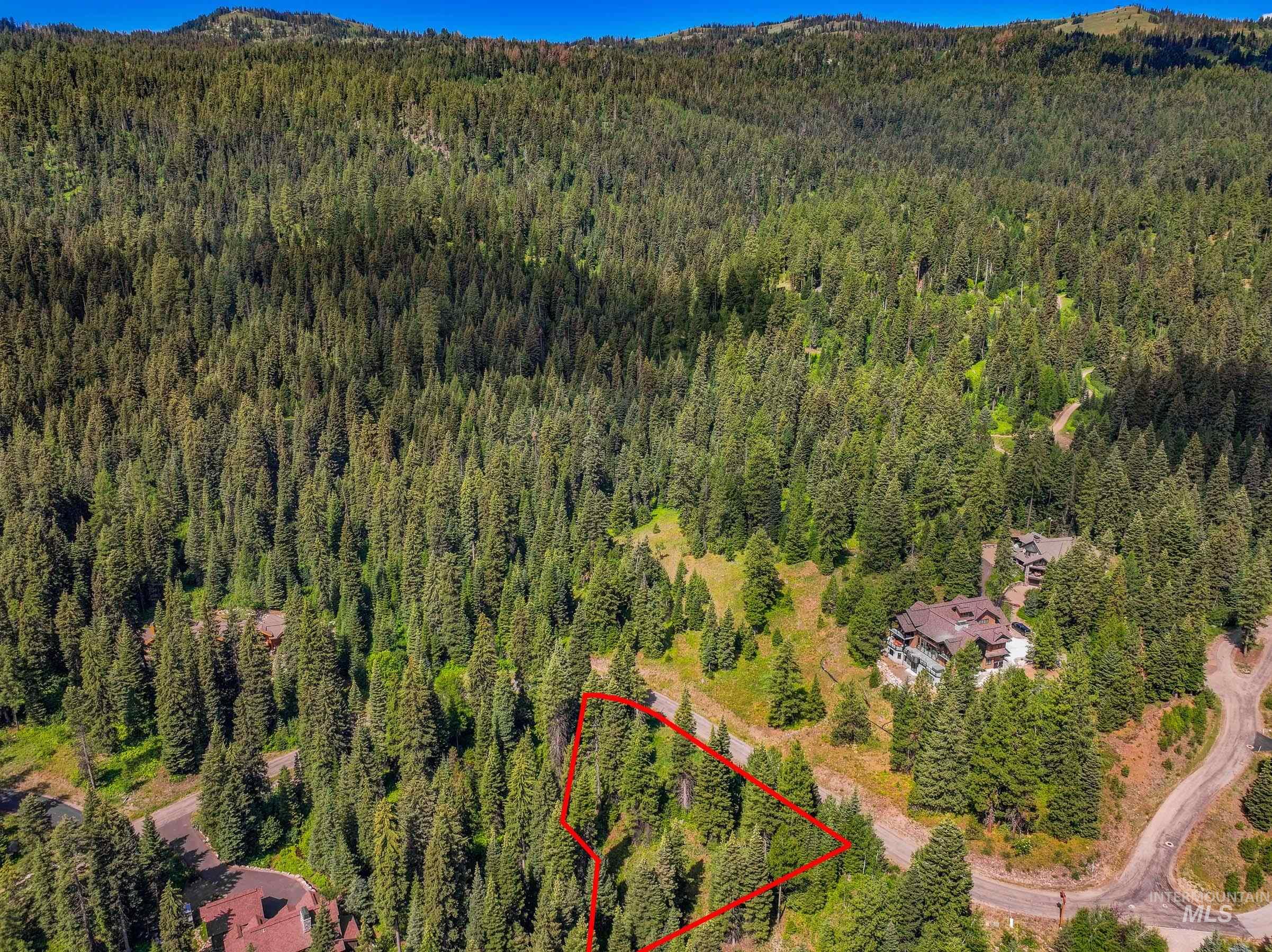 Aerial overview of property's location with property boundaries highlighted and a mountainous background