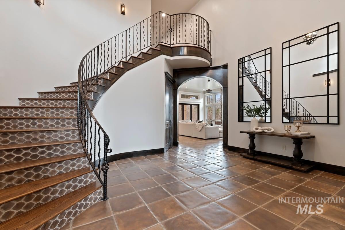 Entryway featuring stairway, a high ceiling, dark tile patterned flooring, and arched walkways