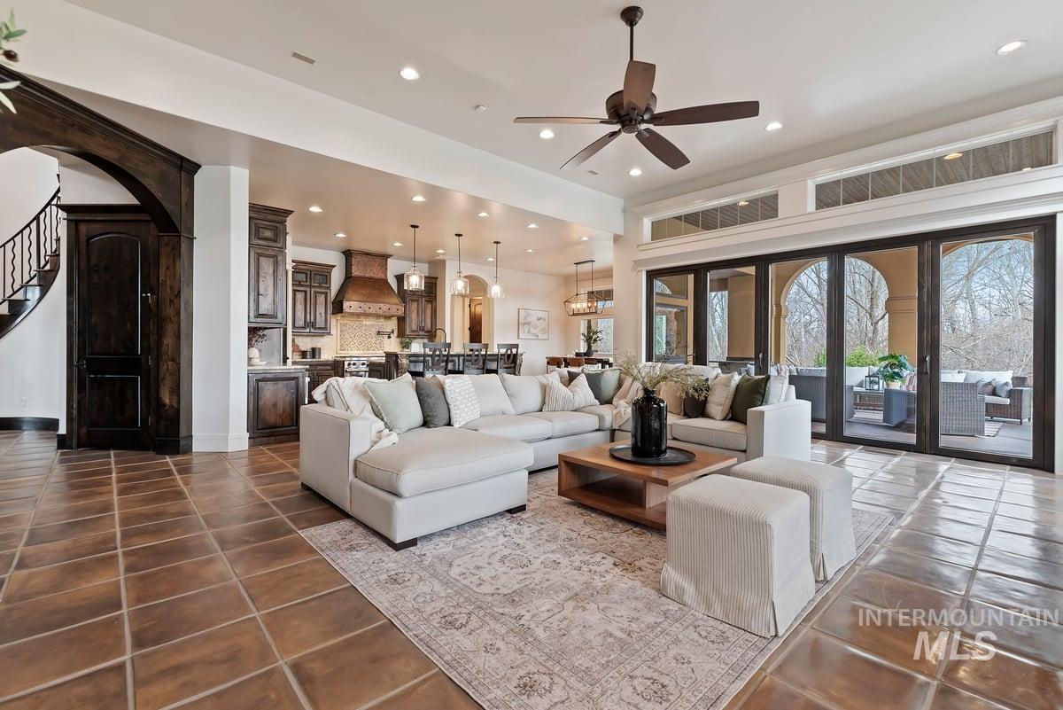 Living area featuring arched walkways, a ceiling fan, stairs, recessed lighting, and dark tile patterned floors