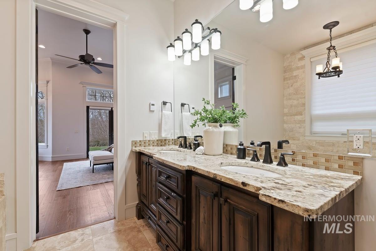 Full bathroom with decorative backsplash, double vanity, healthy amount of natural light, and ensuite bath