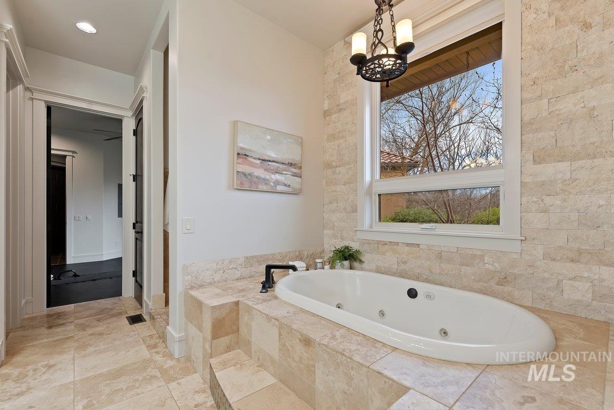 Bathroom featuring a whirlpool tub and a chandelier