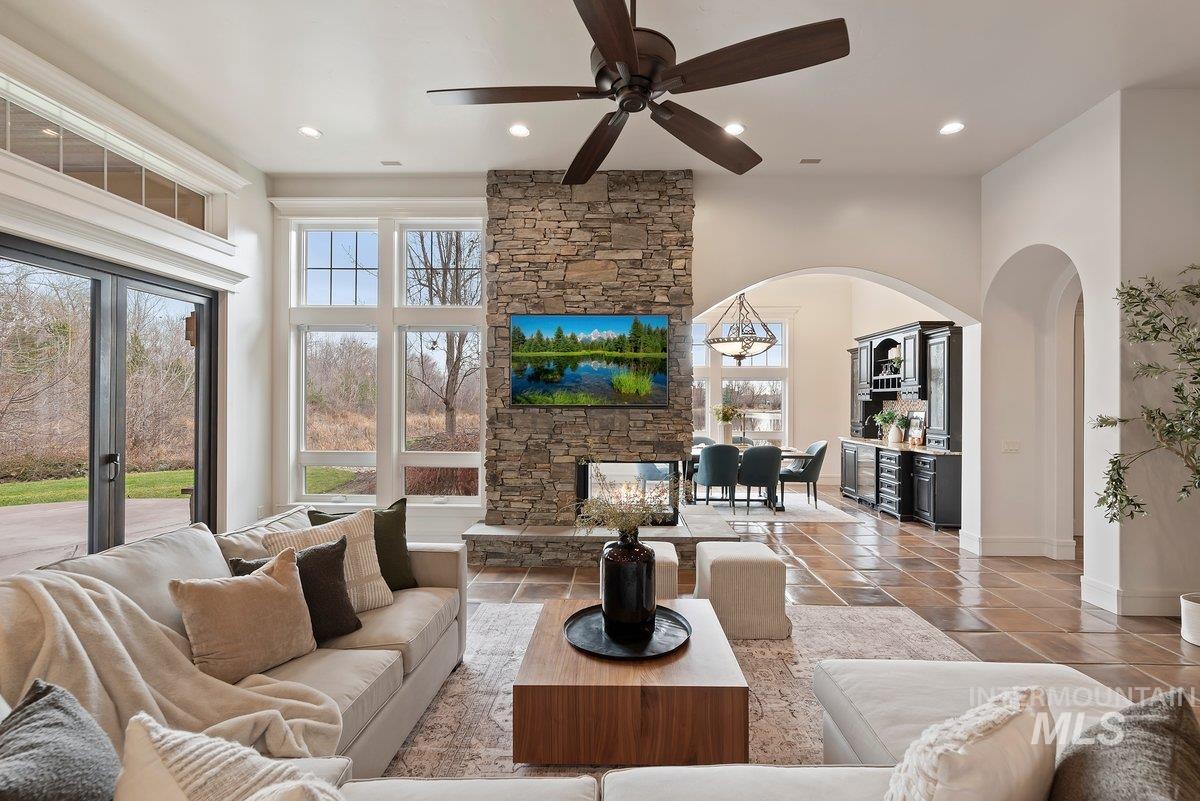 Living area with ceiling fan, recessed lighting, tile patterned flooring, arched walkways, and a fireplace