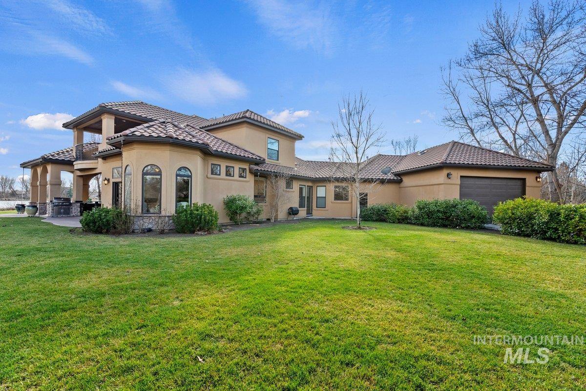 View of front facade featuring stucco siding, a front yard, a garage, and a tiled roof