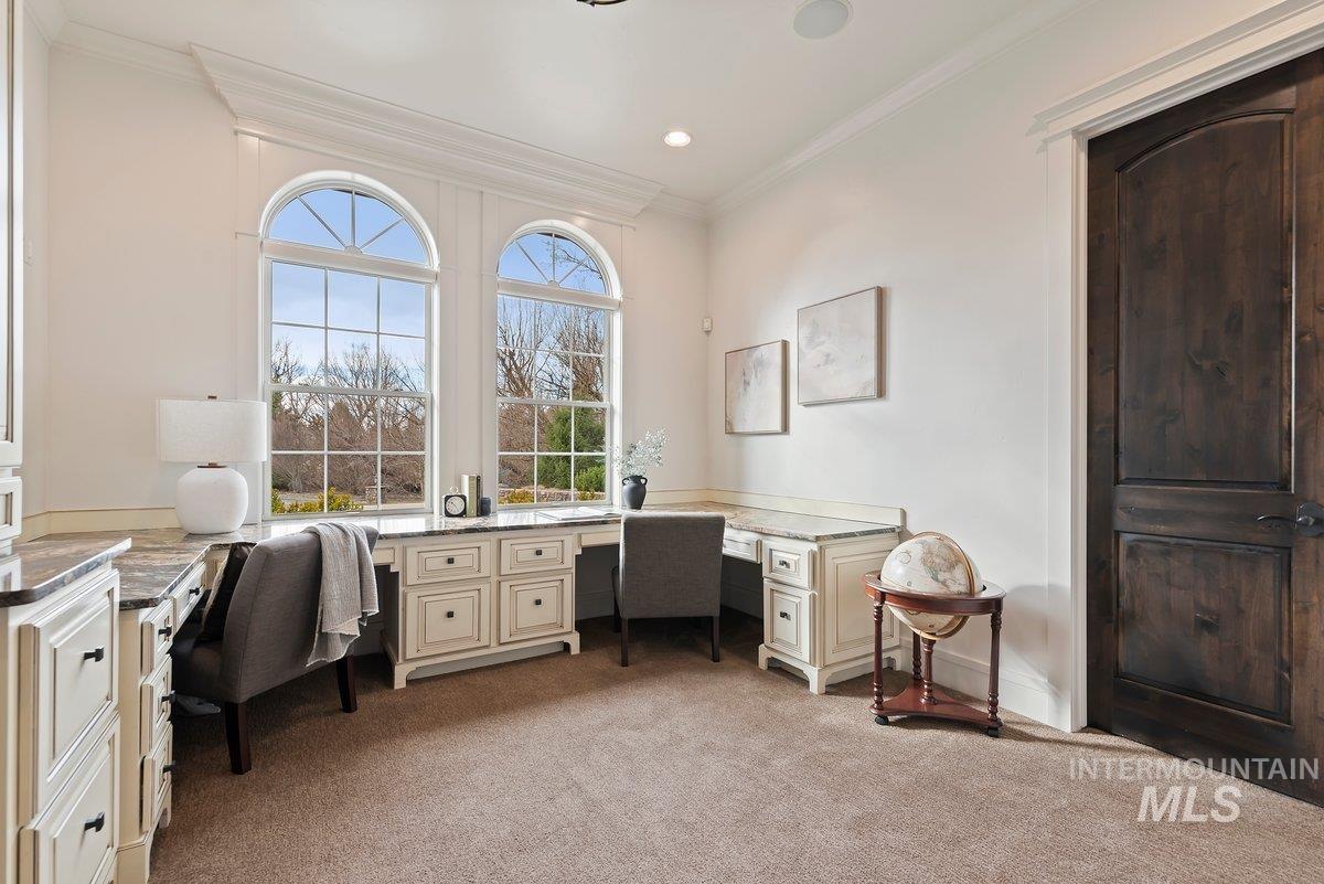 Office space with light carpet, ornamental molding, and built in desk