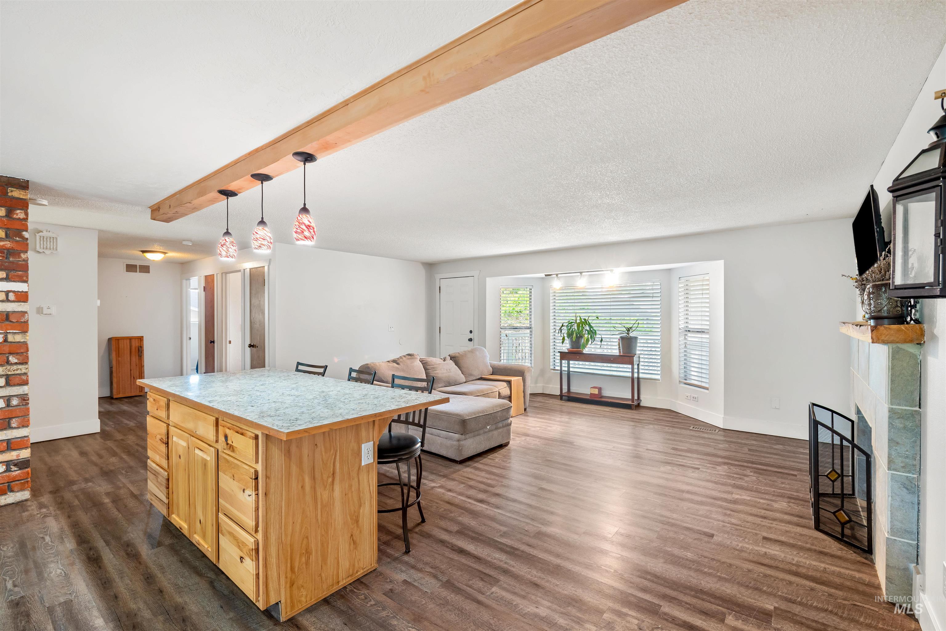 Kitchen featuring a large fireplace, light countertops, beamed ceiling, dark wood-style floors, and a kitchen island