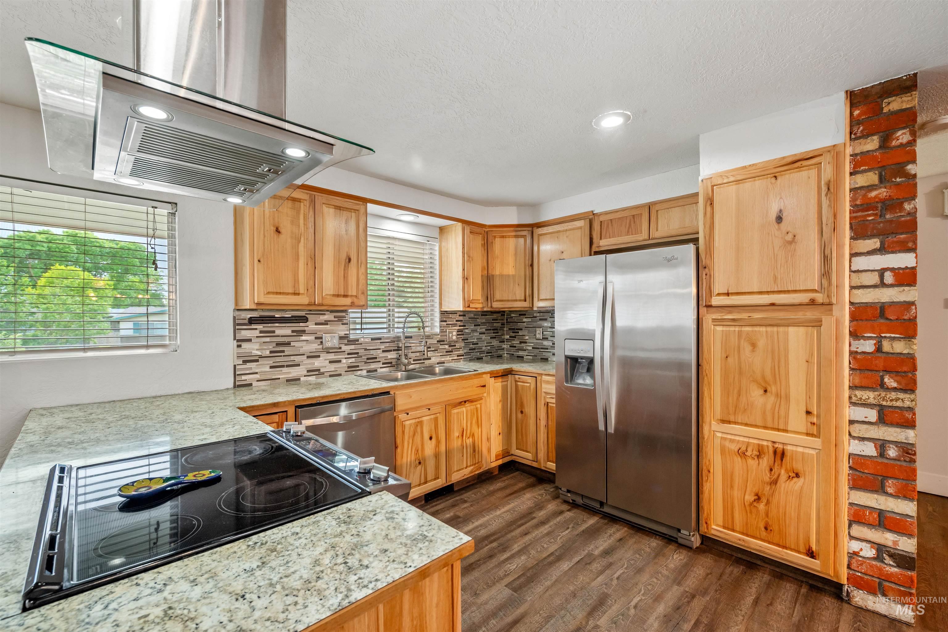 Kitchen featuring light countertops, appliances with stainless steel finishes, exhaust hood, tasteful backsplash, and recessed lighting