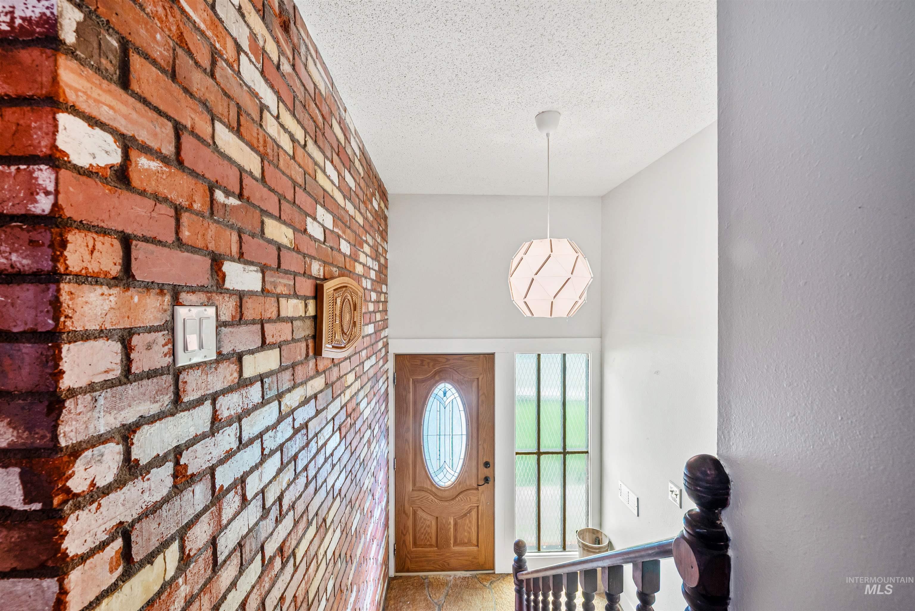 Entryway with a textured ceiling and brick wall