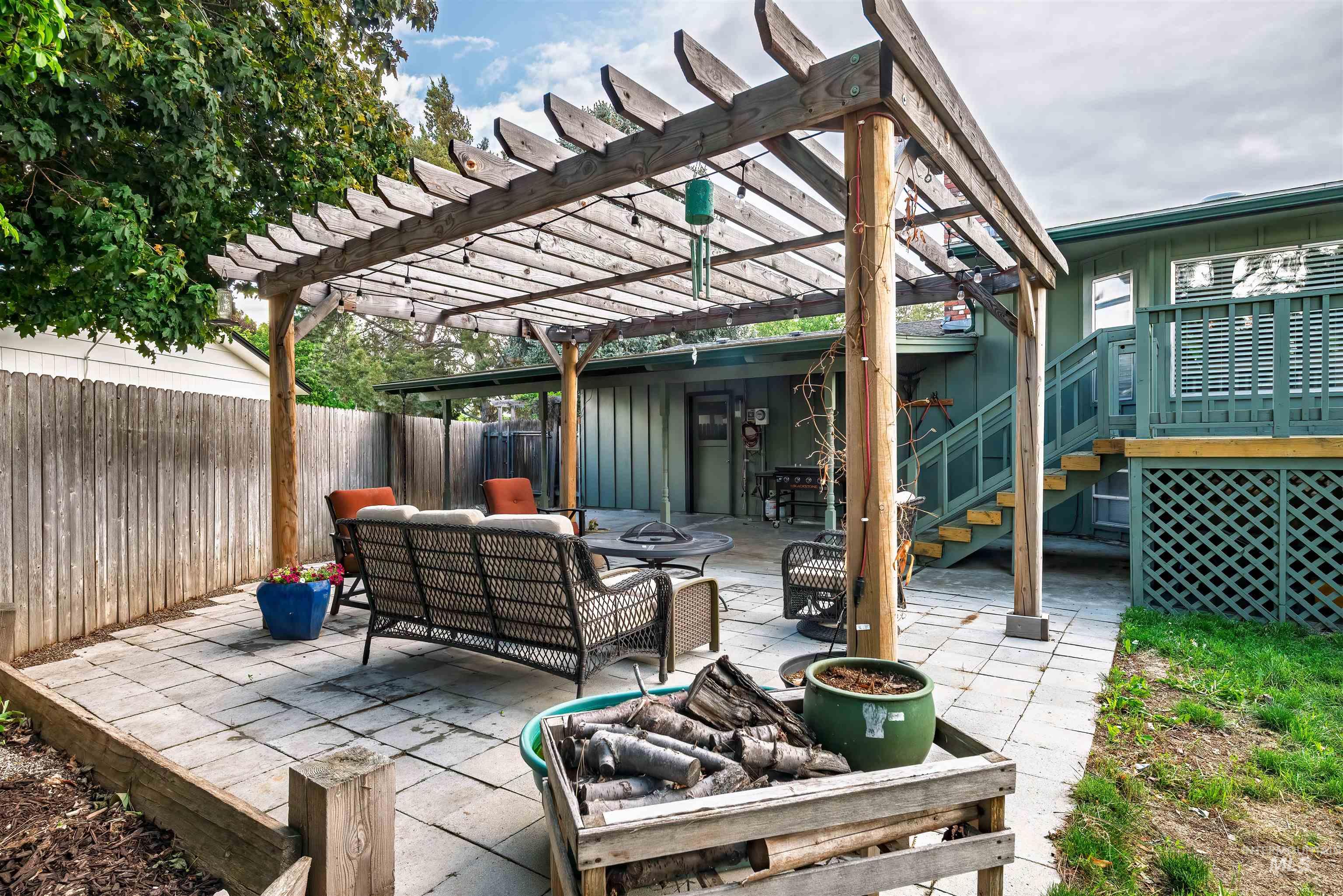 Fenced backyard featuring a pergola, a patio, an outdoor living space with a fire pit, and a wooden deck